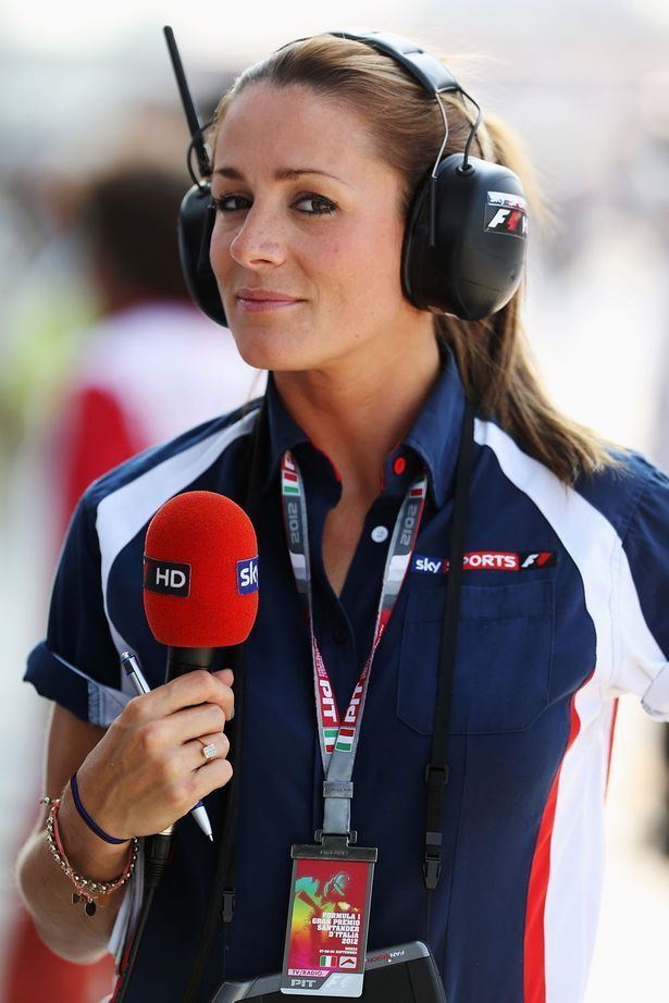 Natalie Pinkham wearing a headphone, a ring, bracelets, and a blue and white polo shirt while holding a ballpen and a red microphone.