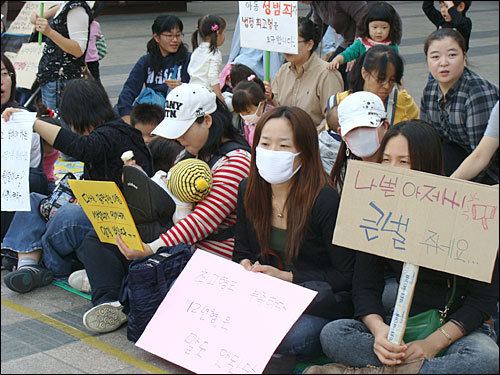 A group of mothers sitting on the street with posters while protesting for the Na-young case ruling