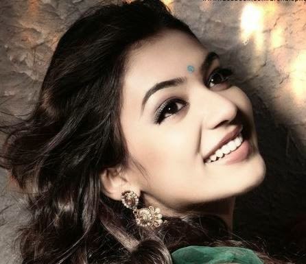 Nazriya Nazim smiling with wavy hair with a golden earring and wearing a green dress.
