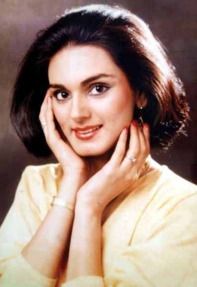 Neerja Bhanot smiling while hands on her face and wearing a yellow blouse, wristwatch, earrings, and ring