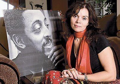 Negrita Jayde smiling and sitting on the couch with a photo of Gregory Hines in black and white