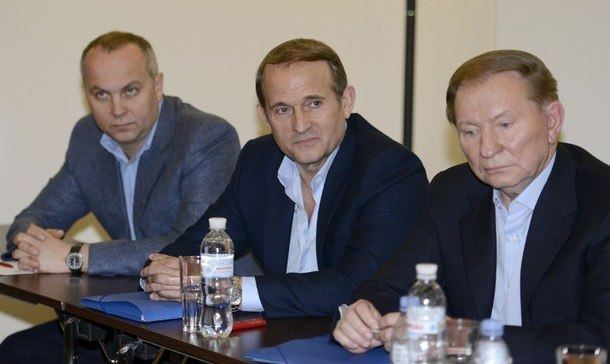 Nestor Shufrych, Viktor Medvedchuk, and Leonid Kuchma (from left to right) with serious faces during informal peace talks with pro-Russian separatists of the self-proclaimed "Donetsk People's Republic". Nestor wearing a gray coat over blue long sleeves, Viktor wearing a dark blue coat over white long sleeves while Leonid is wearing a black coat over white long sleeves.