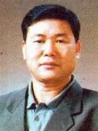 Đặng Trần Côn with a serious face and wearing a gray coat over light green long sleeves.