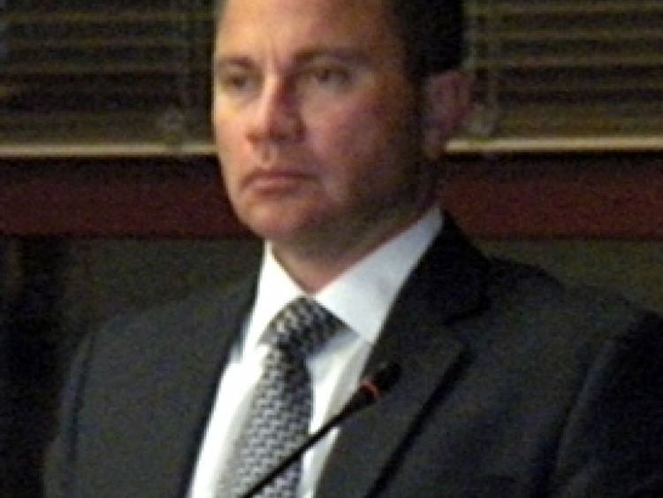 Nicholas Wahl looking afar while wearing a black coat, white long sleeve, and gray necktie