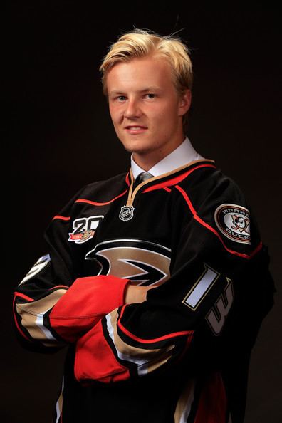 Nick Sorensen smiling while wearing white long sleeves and black and red printed sweatshirt