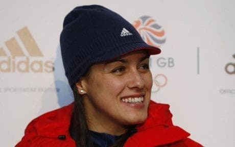 Nicola Minichiello smiling and looking afar while Adidas and Team GB's logo is in the background. Nicola is wearing a black Adidas cap, earrings, and a black shirt under a red jacket