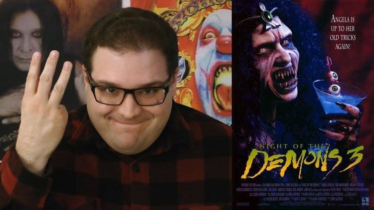 On the left is a fat guy smiling and showing his three fingers with posters in the background, wearing a black and red checkered shirt, and eyeglasses while on the right is A movie poster of the 1988 film Night of the Demons 3 featuring Amelia Kinkade holding a glass of wine with a stick of eyeballs on it, having a curly hair, pointed teeth, black nail polish, and wearing a red oval ring and a headdress