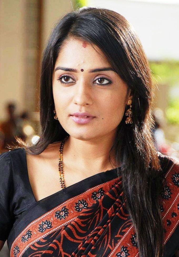 Nikita Thukral wearing earrings, a necklace, and a black and orange dress.
