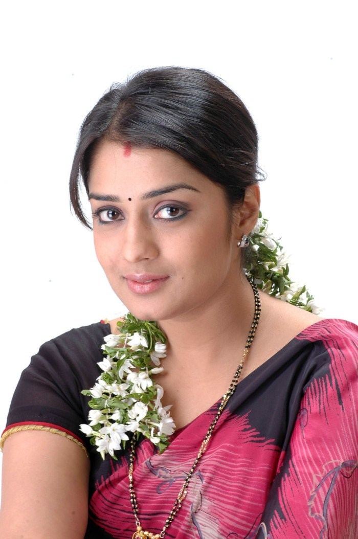 Nikitha Thukral wearing a black and pink dress, earrings, and a necklace with flowers on her hair.