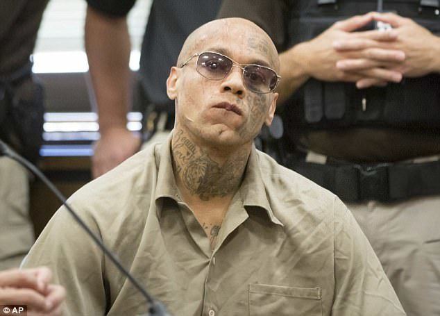 Nikko Jenkins wearing black glasses, police at his back