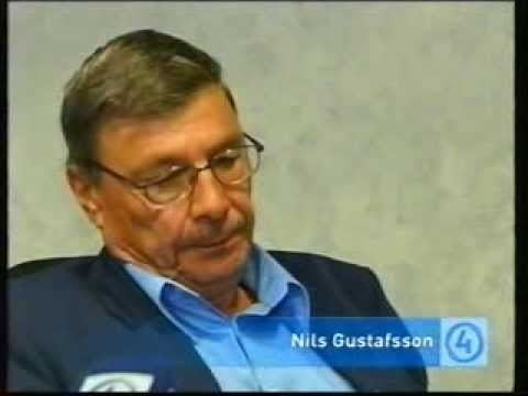 Nils Gustafsson wearing black coat, blue long sleeves and eyeglasses in one of his interviews