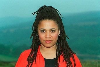 Nimmy March with her braided hair wearing a black shirt and a red long-sleeved shirt in the mountain