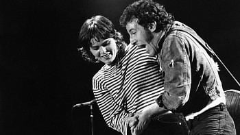Nini Stoltenberg dancing with Bruce Springsteen on stage during his concert with Nini having short hair and wearing a stripe sleeve shirt while Bruce having curly hair and wearing a coat