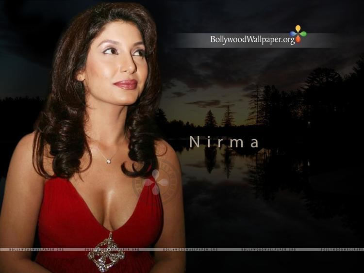 Nirma with a tight-lipped smile while looking at something and wearing a red sleeveless dress and necklace