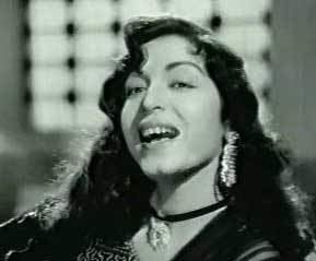 Nishi smiles while wearing an earrings and a necklace in black and white