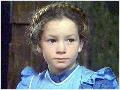 Young Noley Thornton as Heide with a serious face and wearing a blue dress in a scene from Heide, a 1993 American television miniseries.