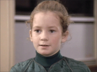 Young Noley Thornton as Clara Sutter with a serious face and wearing a green dress in a scene from "Imaginary Friend" (1992), a 22nd episode of the fifth season of the American science fiction television series Star Trek: The Next Generation.