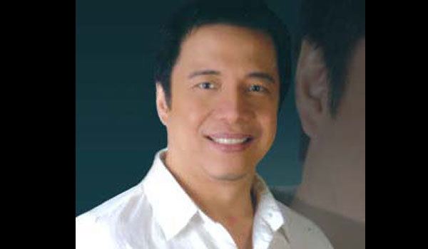 Nonoy Zuniga smiling and wearing a white buttoned polo shirt.