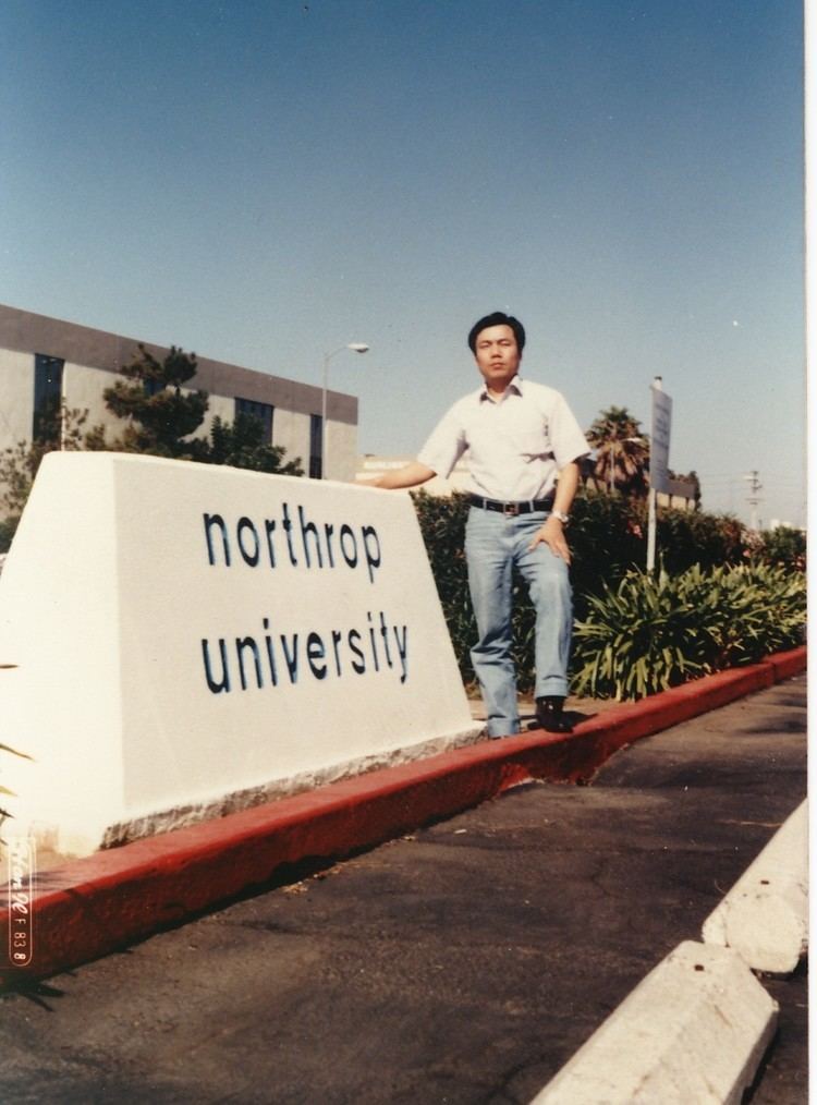 A man standing beside Northrop University signage