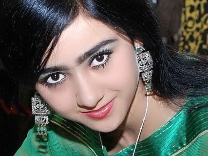 Noziya Karomatullo with a tight-lipped smile while wearing a green blouse, earrings, and necklace