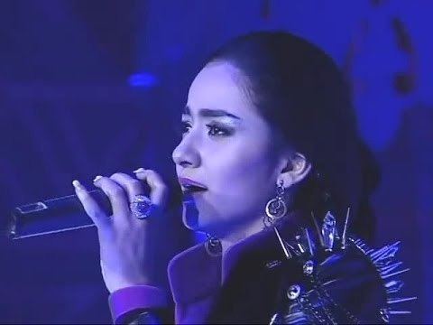 Noziya Karomatullo singing while wearing an earring, ring, and black jacket with thorn on the shoulder
