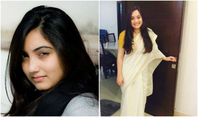 2 images of Nupur Sharma, on the left she is smiling with her black hair and nose piercing wearing a gray shirt, on the right, she is also smiling and holding the doorknob in her left hand with a dining table in the background, has a black hair, a nose piercing wearing a bracelet and a yellow and white saree