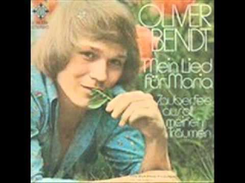 Oliver Bendt holding leaves while wearing a blue log sleeve on the album cover of "Mein Lied Für Maria"