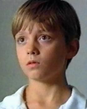 A young Oliver Lofteen looking at something and wearing a white polo shirt.