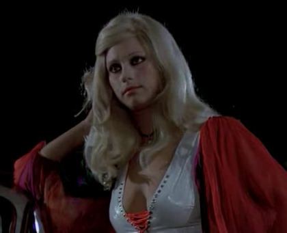 Orchidea De Santis looking at something and wearing a white nightgown under a red robe in the 1974 Italian film Per Amare Ofelia