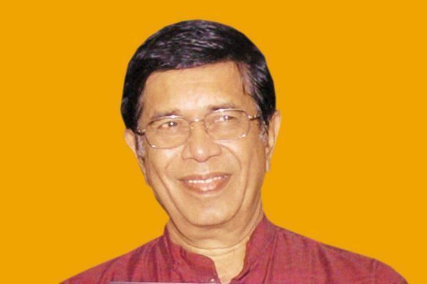 Oscar Fernandes smiling while wearing eyeglasses and red polo