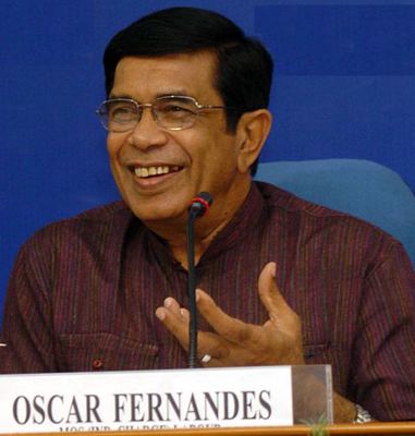 Oscar Fernandes laughing while wearing maroon long sleeves and eyeglasses