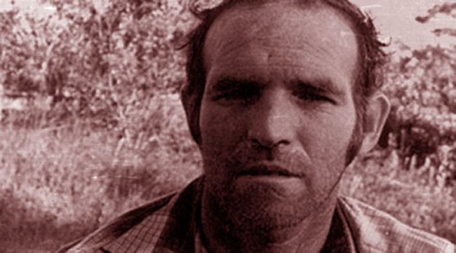 Ottis Toole with a blank facial expression and wearing a striped collared polo shirt.