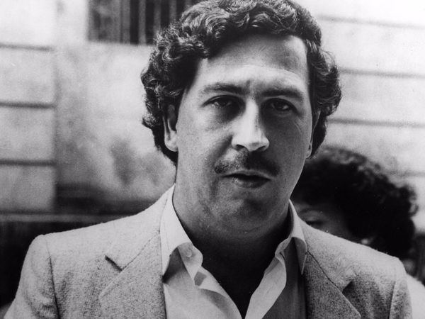Pablo Emilio Escobar Gaviria with a mustache, curly hair, and wearing a suit.