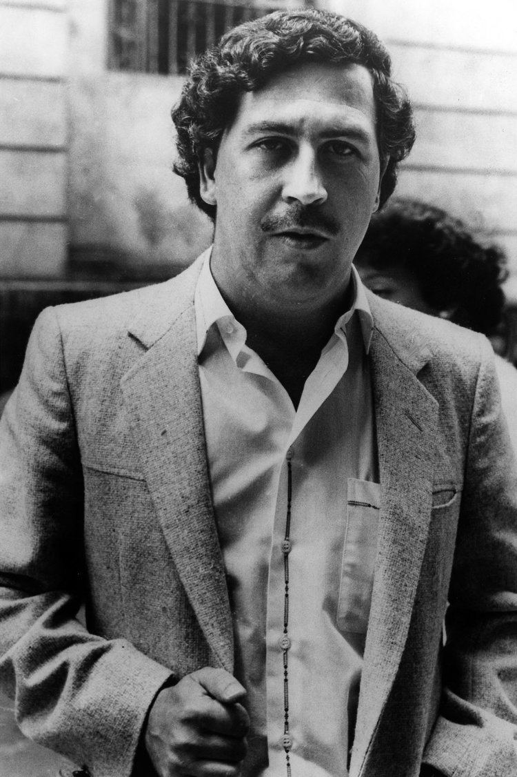 Pablo Emilio Escobar Gaviria with a mustache, curly hair, and wearing a suit.