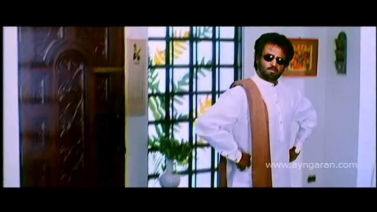 Rajinikanth wearing white long sleeves, black shades, and brown sash in a movie scene from the 1999 film Padayappa