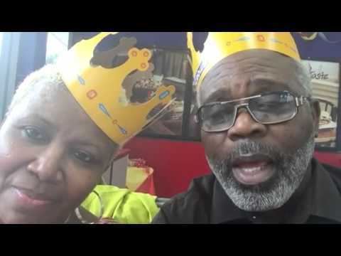 A woman wearing a yellow crown and beside her is a man wearing eyeglasses and a yellow crown