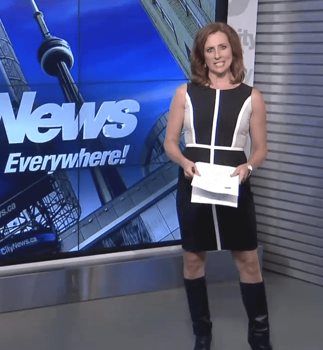Pam Seatle at work as news presenter while wearing black and white dress and black boots
