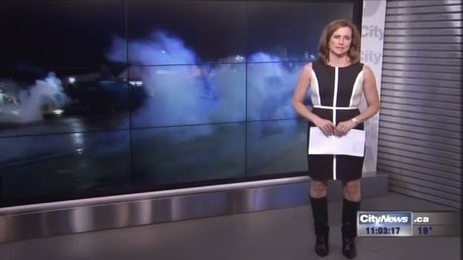 Pam Seatle at work as news presenter while wearing black and white dress and black boots