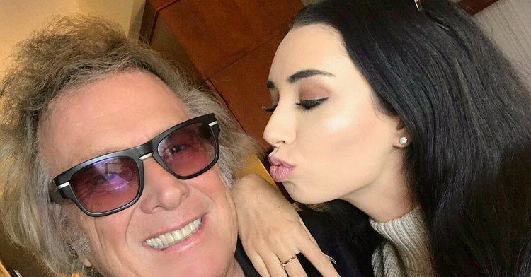 Don McLean smiling and wearing brown shades while Paris Dunn kissing him