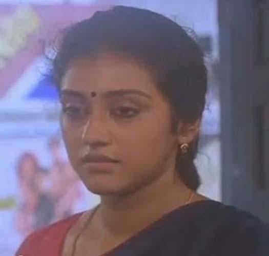 Parvathy Jayaram is serious, has black hair and a bindi, wearing silver earrings, a necklace, a red blouse, and a black saree.