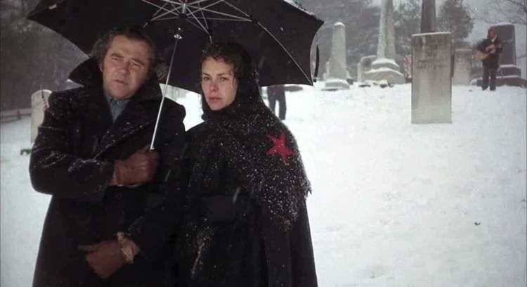 Pat Quinn (actress) with James Broderick holding an umbrella while walking in snow in a movie scene from Alice's Restaurant (1969)