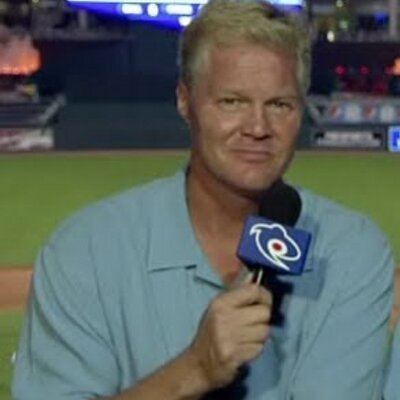 Pat Tabler smiling while holding a microphone and wearing a blue polo shirt