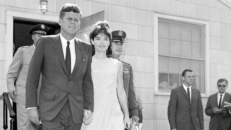 Patrick Bouvier Kennedy looking afar and Jacqueline Kennedy smiling while walking hand in hand