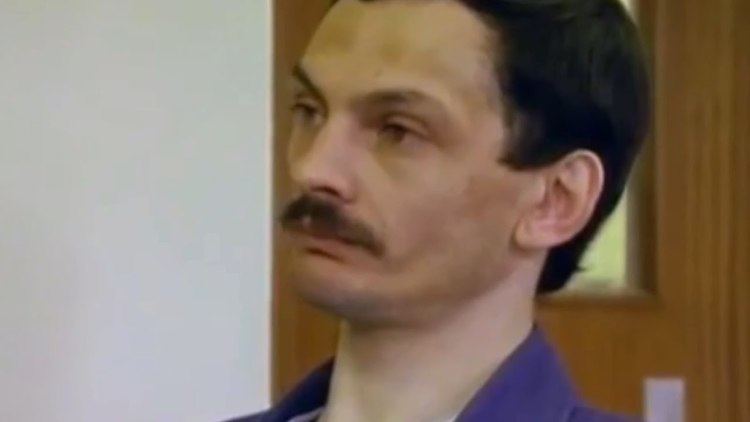 Patrick Mackay, with his mustache, wearing a blue shirt inside the prison