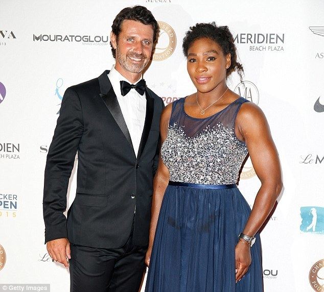Patrick Mouratoglou wearing a black suit, black bow tie, white shirt, and black pants while Serena Williams wearing a necklace, and a blue sleeveless dress.