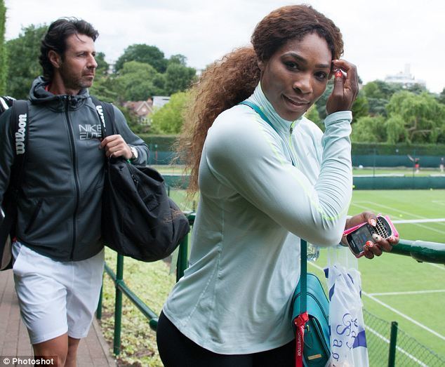 Patrick Mouratoglou wearing a black jacket and white shorts while carrying a black bag together with Serena Williams with curly hair and wearing mint green sportswear, black shorts, and carrying a bag with a mobile phone on her hand.