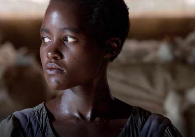 Lupita Nyong'o as Patsey, looking afar while wearing a faded blue blouse in the 2013 biographical drama film, 12 Years a Slave