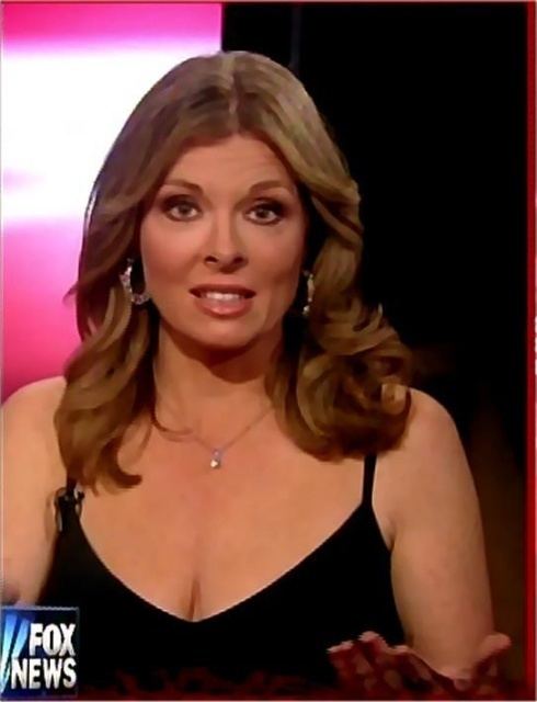Patti Ann Browne is serious, has wavy blonde hair, mouth half opened, with a microphone on the right part of her dress, left palm up, wearing silver earrings, a silver necklace, cleavage showing a black sleeveless dress in the Fox News.