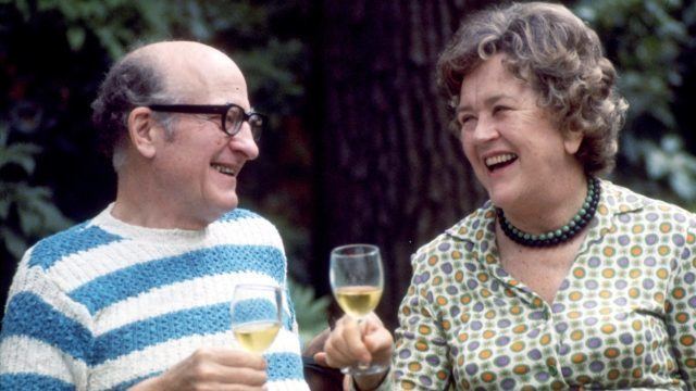 Paul Cushing Child and Julia Child smiling together while holding a glass of wine
