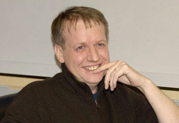 Paul Ferris smiling while wearing a brown jacket